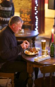 Un uomo seduto a un tavolo con un piatto di cibo di Jacobs Ladder Inn a Falmouth