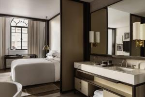 a bedroom with a bed and a sink and a mirror at Capella Sydney in Sydney