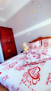 Una cama con un edredón rojo y blanco. en RAMS ENG ROME appartement meublé en Duala