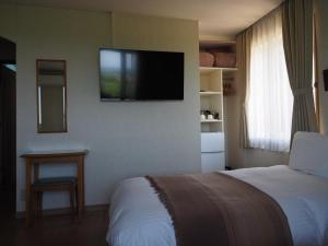 a hotel room with a bed and a television on the wall at Hillside Inn Sirocco in Tateyama