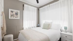a white bedroom with a bed and a window at Salamander Sweet Foreshore Drive in Salamander Bay