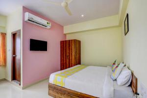 a bedroom with a bed and a tv on the wall at OYO Capital O Swayamkrushi Arcade in Bangalore