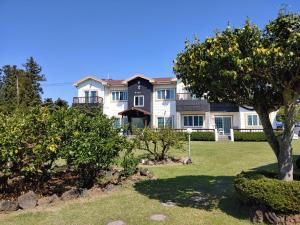 une grande maison avec un arbre dans la cour dans l'établissement Gyulhouse Pension, à Seogwipo