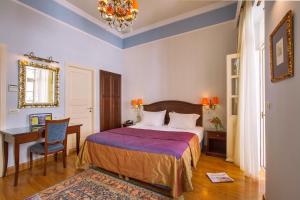 a bedroom with a bed and a desk and a chair at Aetoma Hotel in Nafplio