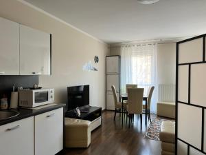 eine Küche und ein Wohnzimmer mit einem Tisch und einer Mikrowelle in der Unterkunft Apartament Villa Concha in Świnoujście