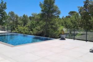 a swimming pool on a patio with trees in the background at Petit paradis sur golf in Flassans-sur-Issole