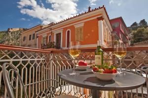 a table with wine glasses and a bowl of fruit on a balcony at Aetoma Hotel in Nafplio