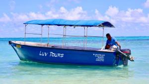 mężczyzna siedzący na niebieskiej łodzi w wodzie w obiekcie LUV TOURS w mieście Centre de Flacq