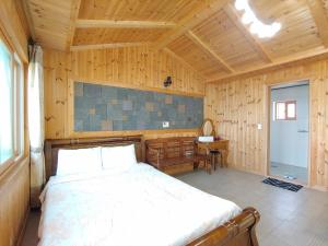 a bedroom with a bed in a wooden room at Gyulhouse Pension in Seogwipo