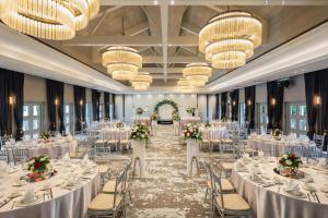 une salle de banquet avec des tables blanches, des chaises et des lustres dans l'établissement The Outpost Hotel Sentosa by Far East Hospitality, à Singapour