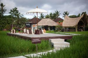 una plataforma de madera con una sombrilla en un campo en Plataran Ubud Hotel & Spa - CHSE Certified, en Ubud