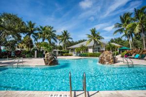 a swimming pool at a resort with palm trees at Catina Golf Condo at the Lely Resort in Naples