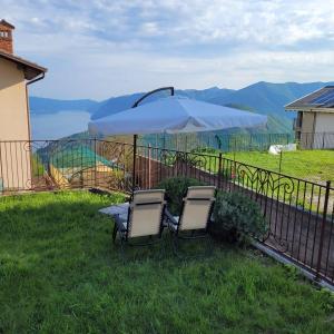 due sedie e un tavolo con ombrellone nell'erba di Peace and Lake Mountain Lake Iseo Hospitality a Bossico