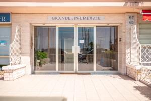 uma porta de vidro de um edifício com um sinal em La Grande Palmeraie - Spacieux studio avec vue mer, terrasse, port de Garavan em Menton