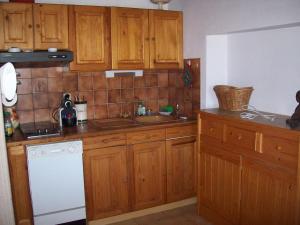 - une cuisine avec des placards en bois et un lave-vaisselle blanc dans l'établissement "Chalet TOURELLE "THORENC, à Andon
