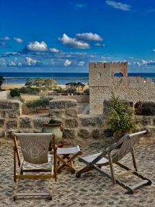 dwa krzesła i stół i krzesła na plaży w obiekcie Domaine El Htouba w mieście Korba
