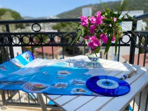 a table with a vase of flowers and a cd at Merve Apartments, your home from home in central BODRUM, street cats frequent the property, not all apartments have balconies , ground floor have terrace with table and chairs in Bodrum City