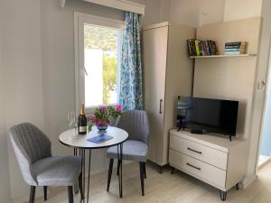 Habitación pequeña con mesa con sillas y TV. en Merve Apartments, your home from home in central BODRUM, street cats frequent the property, not all apartments have balconies , ground floor have terrace with table and chairs, en Bodrum City