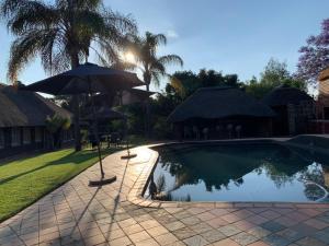 uma piscina com dois guarda-sóis e uma piscina em The Vine Cottage at Viva Connect em Cullinan