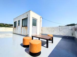 a table and two orange stools on a roof at 酒と宿と不動産-yado- in Yokosuka