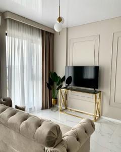 a living room with a couch and a flat screen tv at Mali by the Lake - North Mamaia in Mamaia