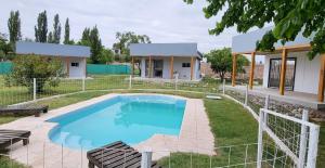 a swimming pool in a yard with a house at Posada y Cabañas "Finca El Rincón de Lunlunta" in Mendoza