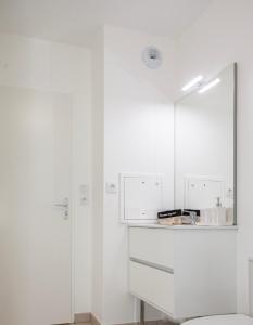 biała łazienka z toaletą i lustrem w obiekcie Echappée belle Osnyssoise w mieście Osny
