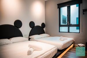 two beds in a room with a window at JOMSTAY Sunway Onsen Suites Ipoh - Lost World of Tambun Ipoh Waterpark in Tambun