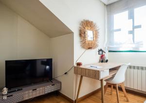 ein Wohnzimmer mit einem TV, einem Tisch und einem Schreibtisch in der Unterkunft Apartamento Irene céntrico con Wifi y parking coche tamaño medio Cangas de Onís in Cangas de Onís