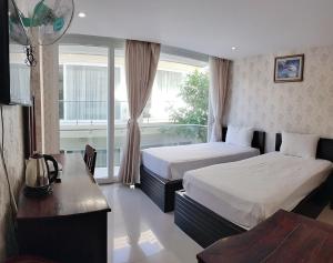 1 dormitorio con 2 camas, escritorio y ventana en Hai Yen Family Hotel, en Mui Ne