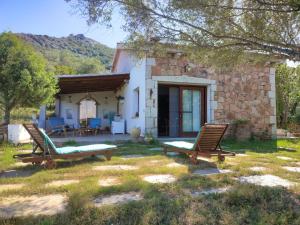 a stone house with two lounge chairs in the yard at Villa Valfrida in San Teodoro