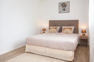 een slaapkamer met een groot wit bed en 2 lampen bij Echappée belle Osnyssoise in Osny