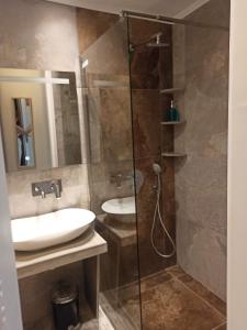 a bathroom with a sink and a glass shower at Katerina's Maisonnette in Loutraki