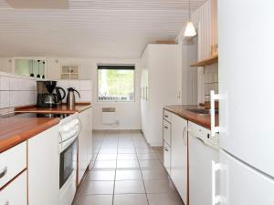 a kitchen with white cabinets and a tile floor at 8 person holiday home in Hemmet in Falen