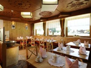 un restaurante con mesas y sillas de madera y ventanas en Vizensn Living, en Sölden