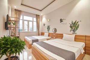 a bedroom with two beds and a potted plant at Bin Bin Hotel 2 - Near Him Lam D7 in Ho Chi Minh City