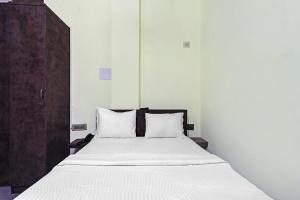 a bed with white sheets and pillows in a room at Collection O Hotel Dhruv Tara Inn in Patna