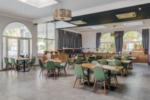ein Restaurant mit Holztischen und grünen Stühlen in der Unterkunft UPTOWN Büyük Anadolu Girne Hotel in Kyrenia