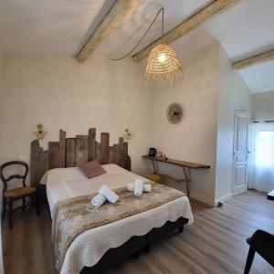 a bedroom with a large bed and a chandelier at MANADE SAINT LOUIS Mas de La Paix in Montcalm