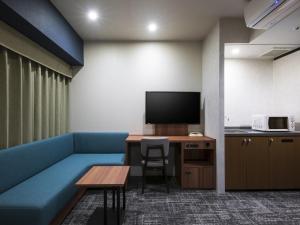 Cette chambre dispose d'un canapé bleu, d'une table et d'une télévision. dans l'établissement Hotel Villa Fontaine Tokyo-Ueno Okachimachi, à Tokyo