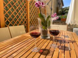 two glasses of wine on a wooden table with a vase of flowers at Villa Grace in La Spezia