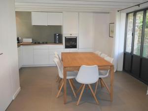 eine Küche mit einem Holztisch und weißen Stühlen in der Unterkunft Maison Locmaria, 3 pièces, 6 personnes - FR-1-418-208 in Locmaria