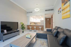 a living room with a couch and a tv at KeyHost - Cozy 1BR Apartment Near Five Hotel - JVC - KG40 in Dubai