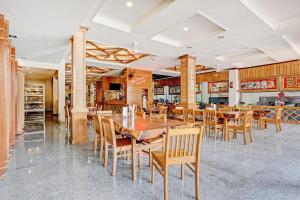 jadalnia z drewnianymi stołami i krzesłami w obiekcie Capital O 90428 Remington Hotel w mieście Palembang