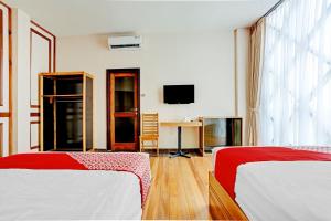 Cette chambre comprend deux lits et une télévision. dans l'établissement Capital O 90428 Remington Hotel, à Palembang
