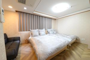 ein Schlafzimmer mit einem großen Bett und einer Couch in der Unterkunft NY Cottage（コテージ） in Tokio