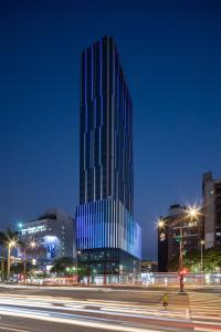 um edifício de vidro alto em uma cidade à noite em Solaria Nishitetsu Hotel Taipei Ximen em Taipei