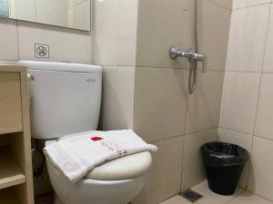 a bathroom with a white toilet and a shower at Alexa at Tanglin Apartemen in Surabaya