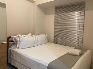 a bedroom with a large white bed with a window at Alexa at Tanglin Apartemen in Surabaya