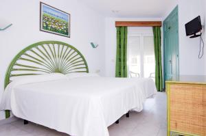 a bedroom with a large white bed and a tv at Hostal Manolo in Garrucha